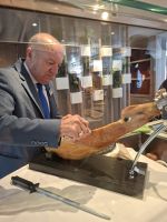 Der Hoteldirektor schneidet den Schinken als Vorspeise an