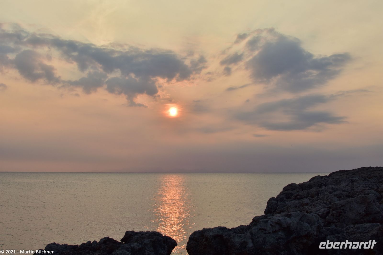 Wanderreise Menorca - Sonnenuntergang in Cala Blanca - In der Luft die Asche des La Palma Vulkans - Blick nach Mallorca &ndash; &copy; Martin Büchner (Eberhardt TRAVEL)