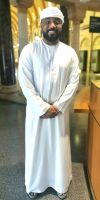 Der nette Museumswächter im islamischen Museum in Sharjah in der traditionellen männlichen Kleidung