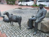 Vor dem Hotel sitzt der Schaftreiber mit seinem Hund und drei Schafen