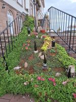 Saint-Hyppolyte - Weinflaschen zieren das Blumenbeet