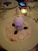 Weiße Schokoladenkugel gefüllt mit Kastanienmousse mit Johannisbeermarmelade verziert mit Beerenpuder und goldenem Blatt