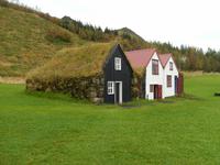 Ein Grassodenhaus neben zwei etwas moderneren Häusern. Häuser wie diese wurden auf Island bis etwa 1950 noch genutzt.