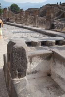Pompei: ein öffentlicher Brunnen und ein antiker Übergang mit modernen Gittern. In der Antike hätten die Gitter die Wagenräder massiv gestört.
