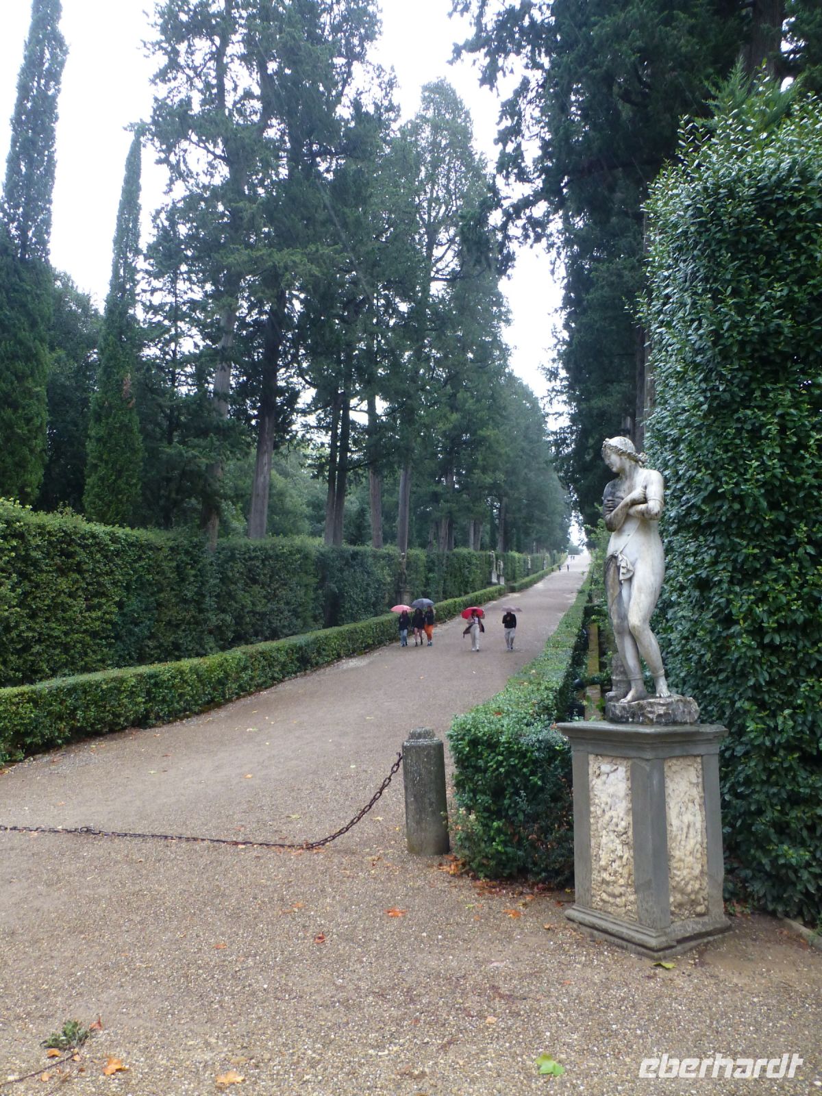 Die Dame friert, die Allee zieht sich durch die Parkanlage.