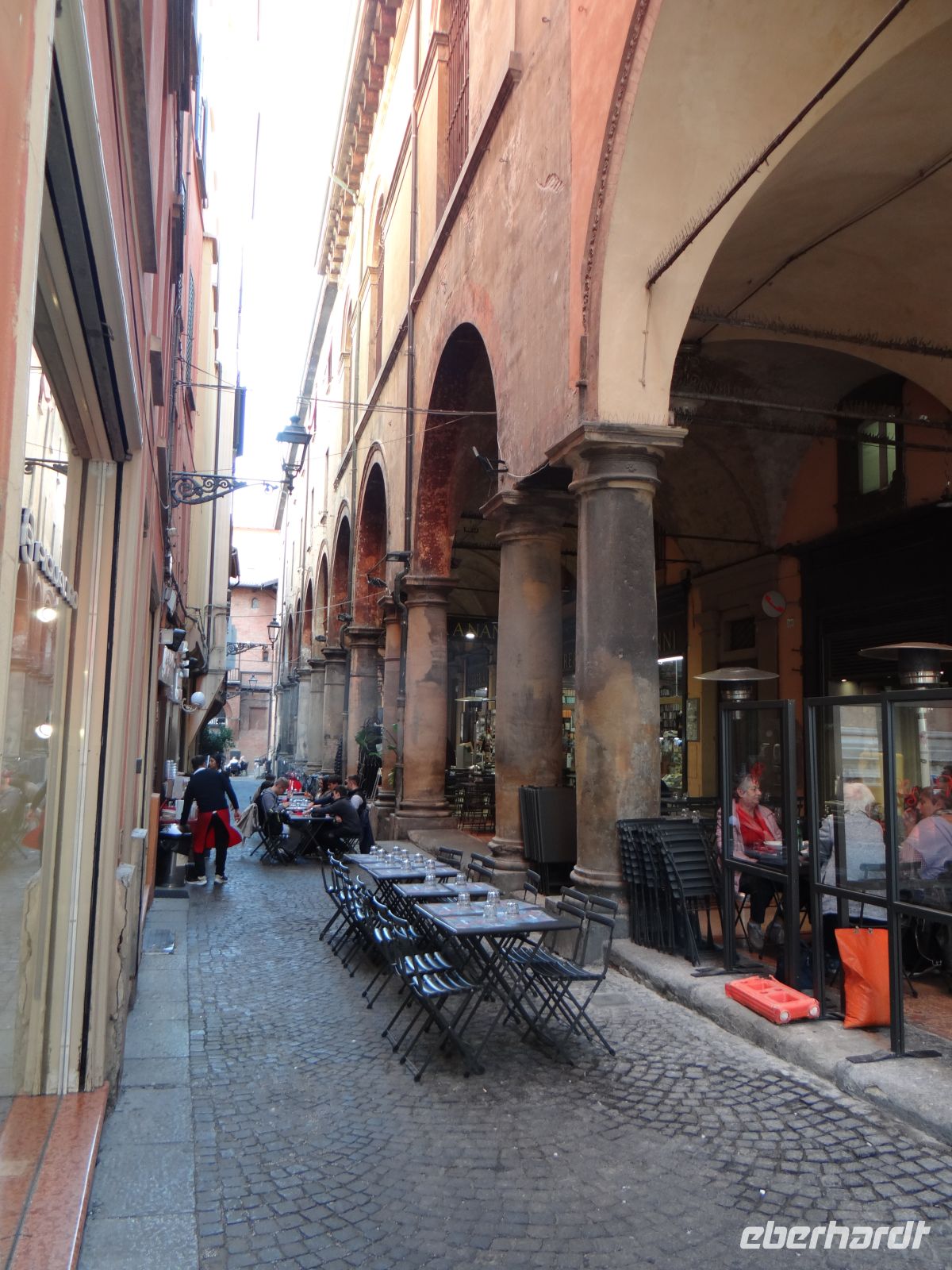 Bologna, Tische unter und vor den Arkaden. Jeder Platz ist schön zum Sitzen und Genießen.