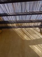 Der Sonnenschutz aus Schilf zeichnet ein feines Muster auf die Wand.