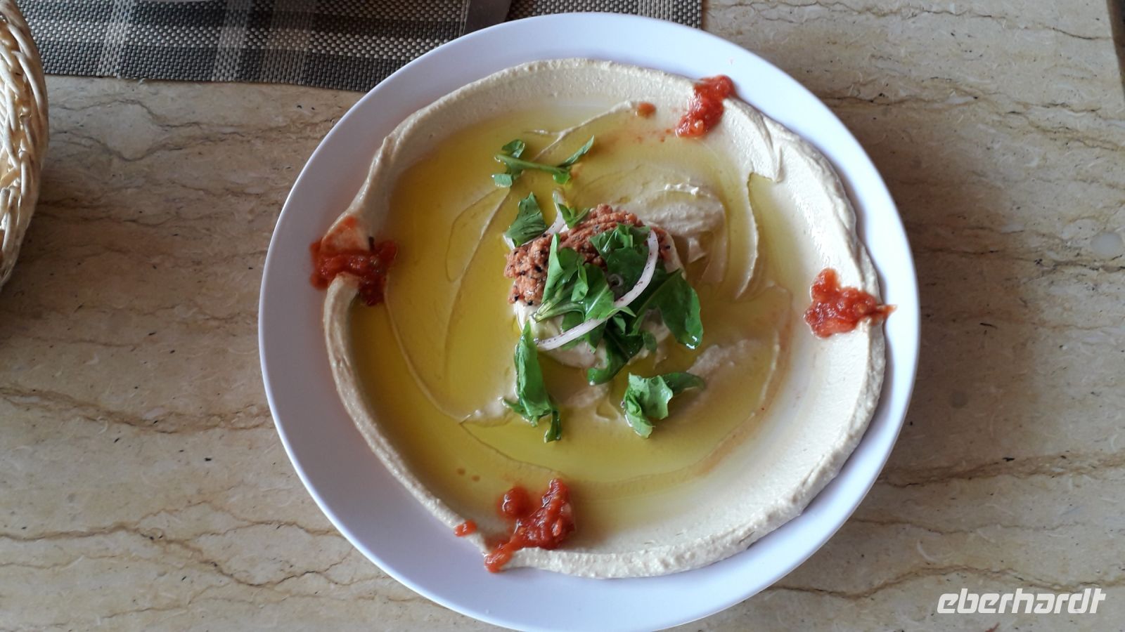 Hummus mit Olivenöl und etwas Salat, dazu Brot