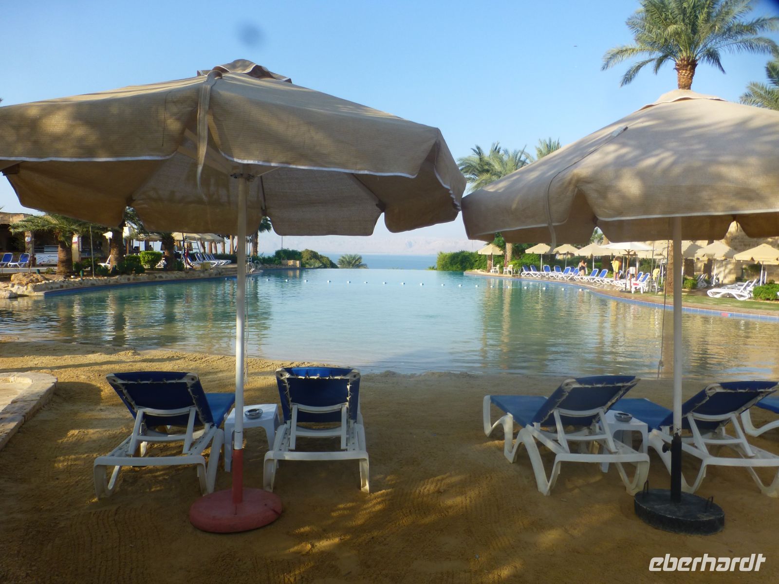 Der Pool ist bereit für seine Gäste, der Poolgrund gereinigt, der Sand gehakt, die Liegen ausgerichtet und die Sonnenschirme aufgespannt. 
