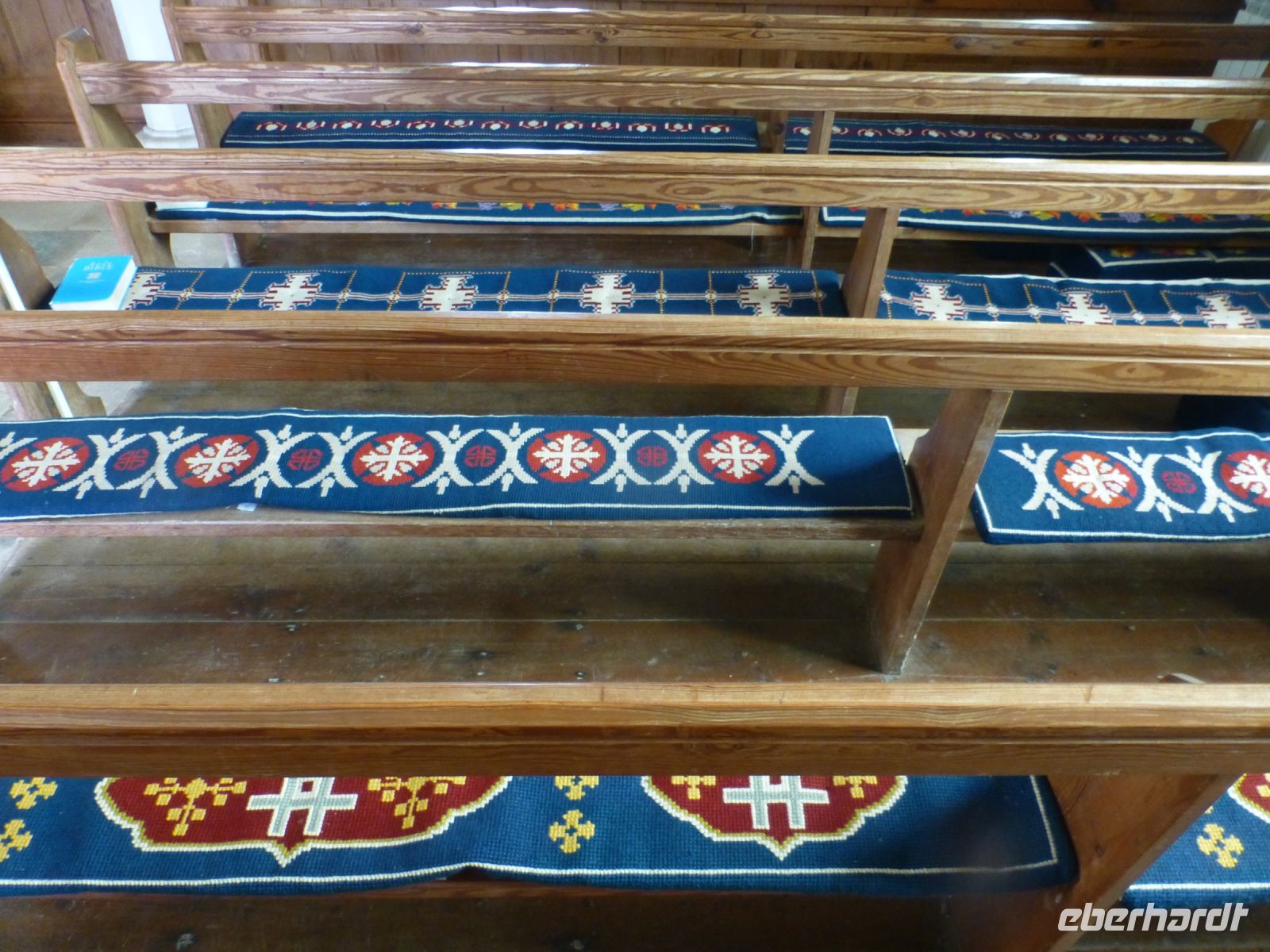 Die Sitzbänke der Kirche sind mit den 40 verschiedenen Wappen der Pachtgrundstücke bestickt. So hat jeder seinen festen Platz.