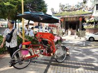 Bunte Rikschah vor einem chinesischen Tempel in Georgetown, Penang