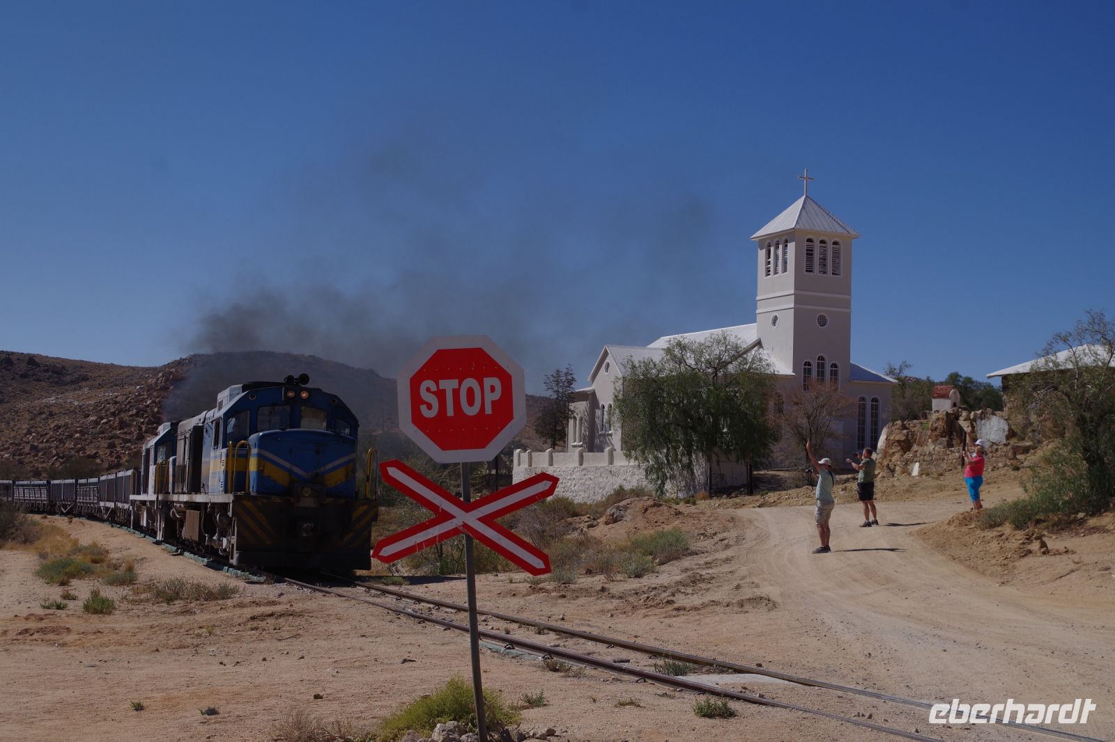 Aus: Kirche, Bahnübergang und fahrender Zug