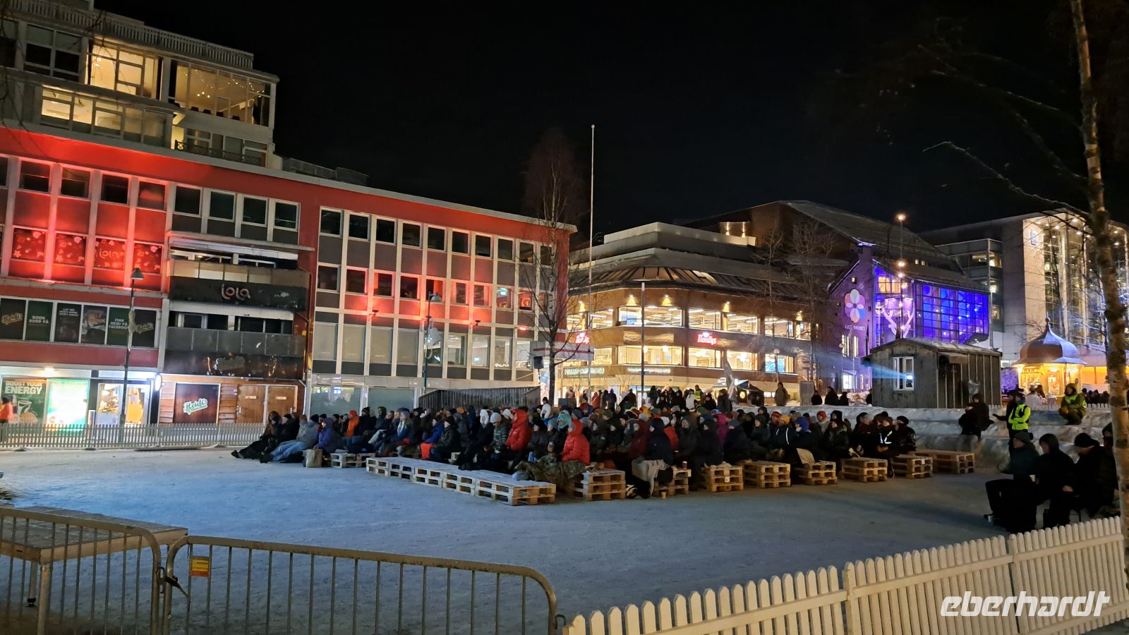 Tromsø - Friluftsliv - Freiluftleben - Filmfestival mitten im Winter auf dem Hauptplatz auf Rentierfellen sitzend
