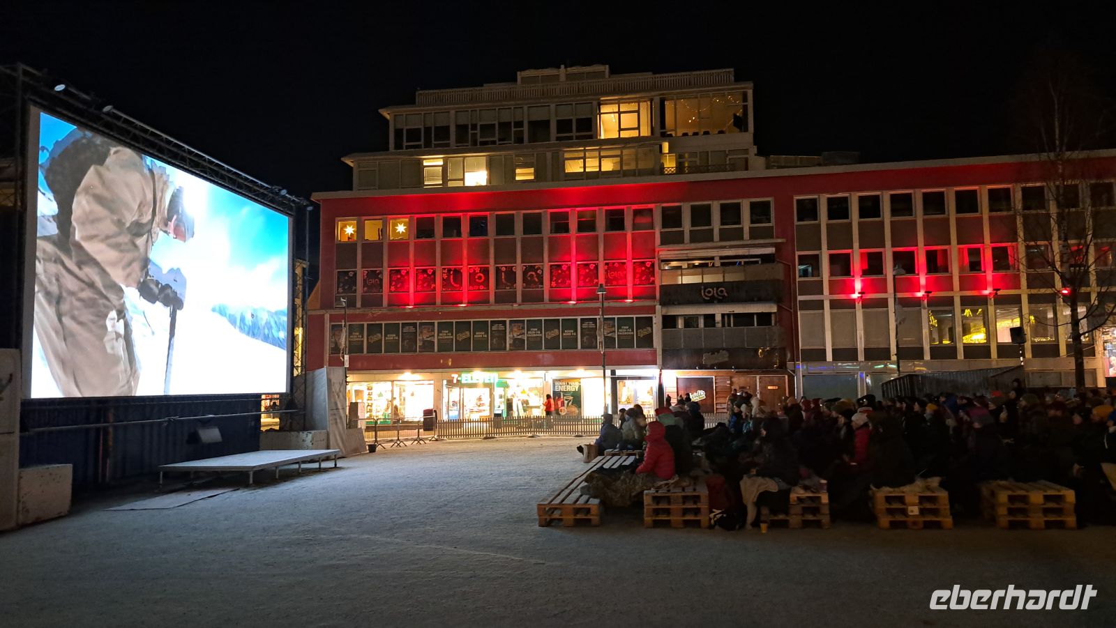 Tromsø - Friluftsliv - Freiluftleben - Filmfestival mitten im Winter auf dem Hauptplatz auf Rentierfellen sitzend