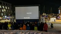 Tromsø - Friluftsliv - Freiluftleben - Filmfestival mitten im Winter auf dem Hauptplatz auf Rentierfellen sitzend