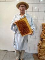 Stolz präsentiert der Imker seine Bienenwabe