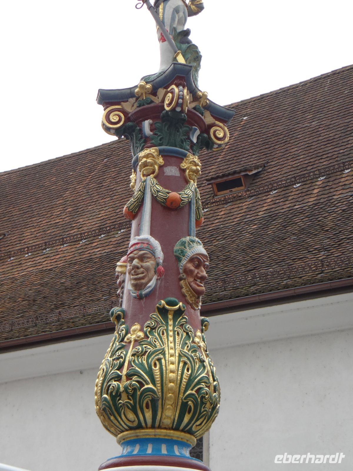 Luzern, der Fritschibrunnen ist rundum mit Fasnachtsmasken geschmückt und oben thront ein Bannerträger.