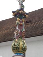 Luzern, der Fritschibrunnen ist rundum mit Fasnachtsmasken geschmückt und oben thront ein Bannerträger.
