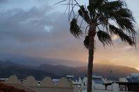 Die Strahlen der aufgehenden Sonne brechen sich in den am Gebirge hängenden Wolken