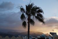 Die Strahlen der aufgehenden Sonne brechen sich in den am Gebirge hängenden Wolken