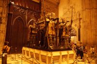 Kolumbusgrab mit den die spanischen Reiche repäsentierenden Schildknappen als Sargträger: Vorne Castilla und León, hinten Aragón, die Fledermäuse stehen für Valencia.