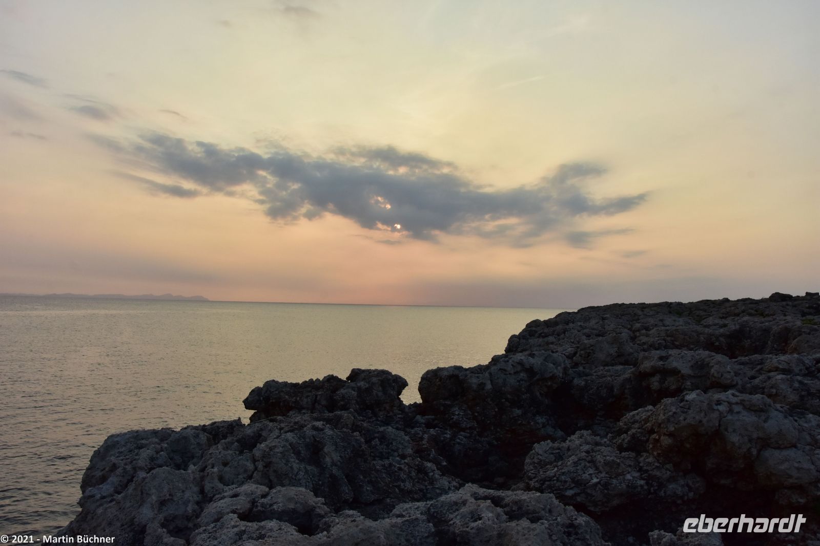 Wanderreise Menorca - Sonnenuntergang in Cala Blanca - In der Luft die Asche des La Palma Vulkans - Blick nach Mallorca