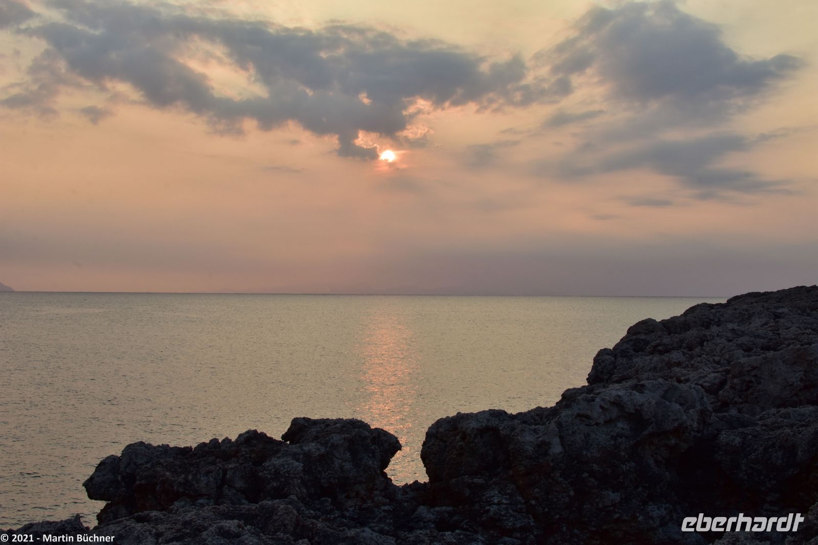 Wanderreise Menorca - Sonnenuntergang in Cala Blanca - In der Luft die Asche des La Palma Vulkans - Blick nach Mallorca
