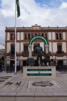 Andalusisches Wappen, skulturiert in Ronda - dahinter das Gebäude, in dem es entworfen wurde