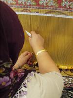 eine Teppichknüpferin bei der Arbeit