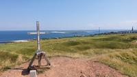 das Gipfelkreuz auf dem Pinneberg mit Blick zur Düne