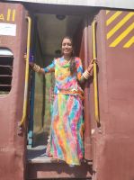 Eine Inderin im farbenfrohen Sari gehüllt auf der Zugfahrt durch das Umland von Jojowar, Rajesthan - Indien