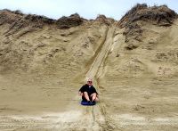 Große Rundreise Neuseeland: Unser Busfahrer Barry beim Sandboarden am Ninety Mile Beach. 