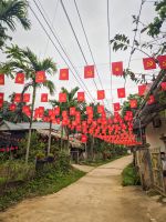 Dorfstraße mit vietnamesischen Flaggen während der Wanderung am Chum River in Pu Luong, Vietnam